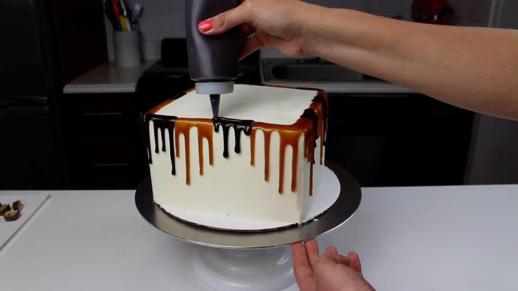 图像的巧克力和焦糖滴被添加到一个士力架滴蛋糕