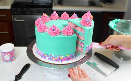 多彩funfetti蛋糕，饰以蓝绿色和粉红色的奶油和丰富多彩的洒