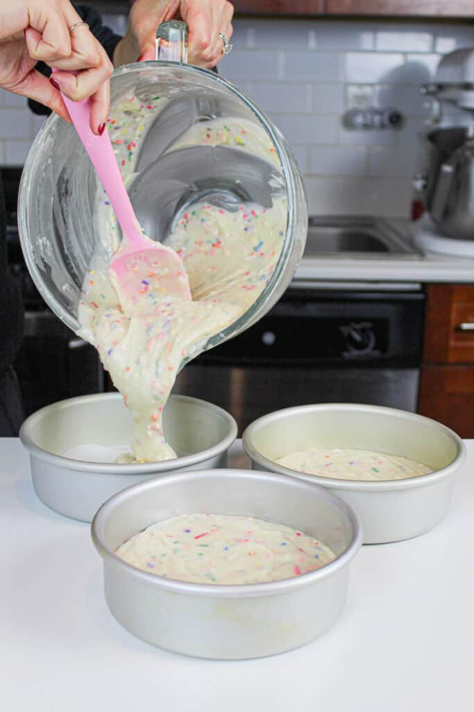 将funfetti蛋糕糊倒入3个6英寸的蛋糕锅中