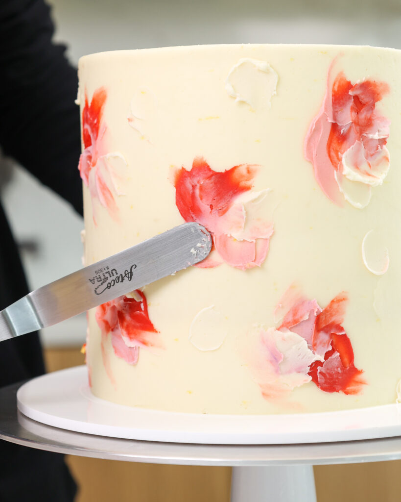 白巧克力覆盆子层蛋糕的图像，上面装饰着五颜六色的黄油