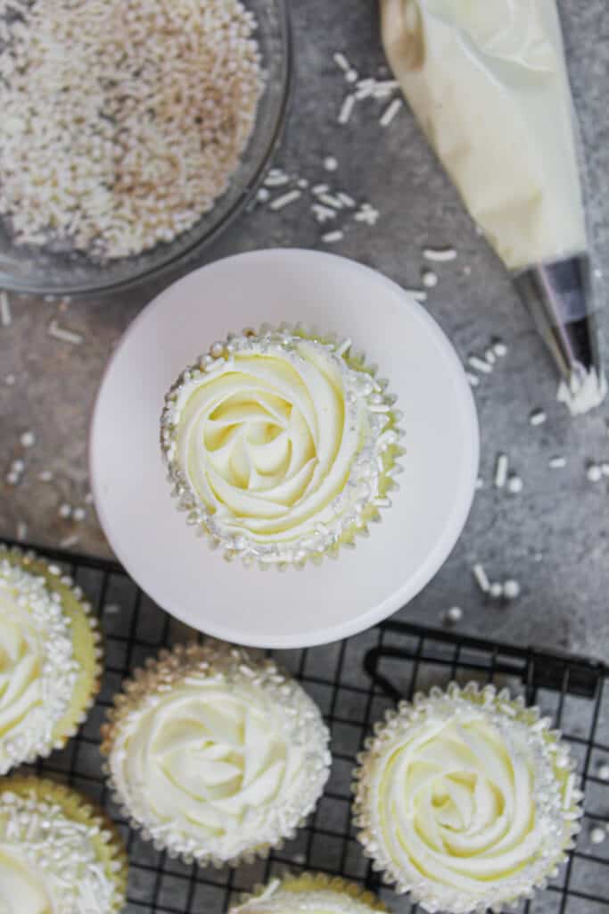 杏仁纸杯蛋糕的图像，装饰有1m糖霜的Wilton 1m和精美的白色撒布混合物