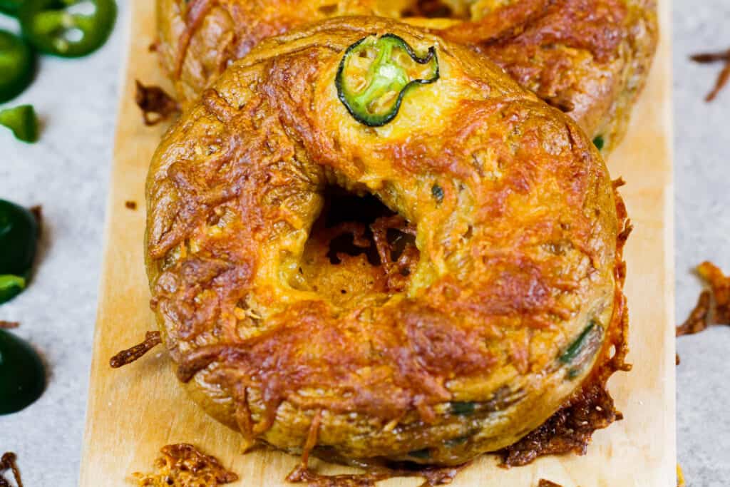 董事会上的墨西哥胡椒切达百吉饼的图像，准备被切割和食用