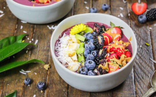 用花生酱做成的巴西莓碗，用新鲜水果、格兰诺拉麦片和一些可食用的花装饰