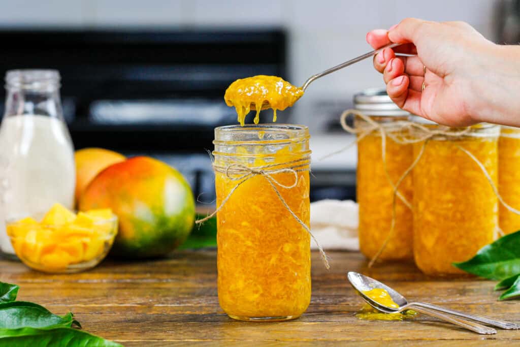 芒果冰箱果酱的图象被匙子从梅森瓶子舀出