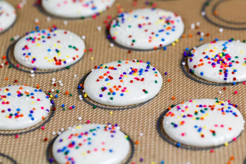 白色马卡龙的外壳上点缀着彩虹色的糖屑，已经准备好烤了