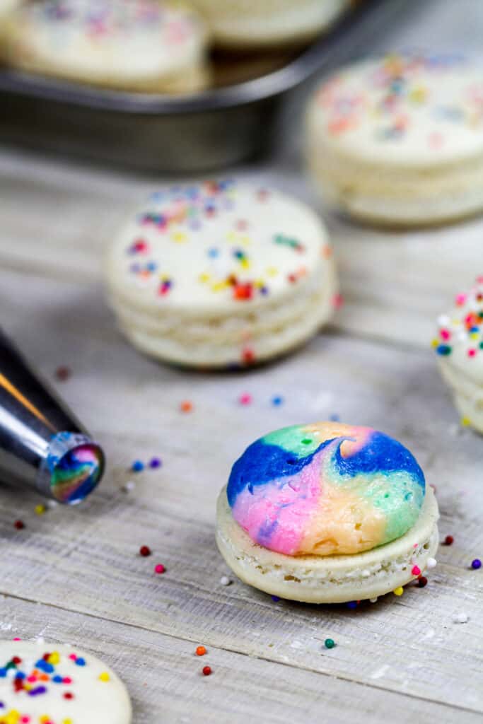 彩虹macaron的图象与彩虹buttercream的准备好准备好与它的第二个macaron壳顶上