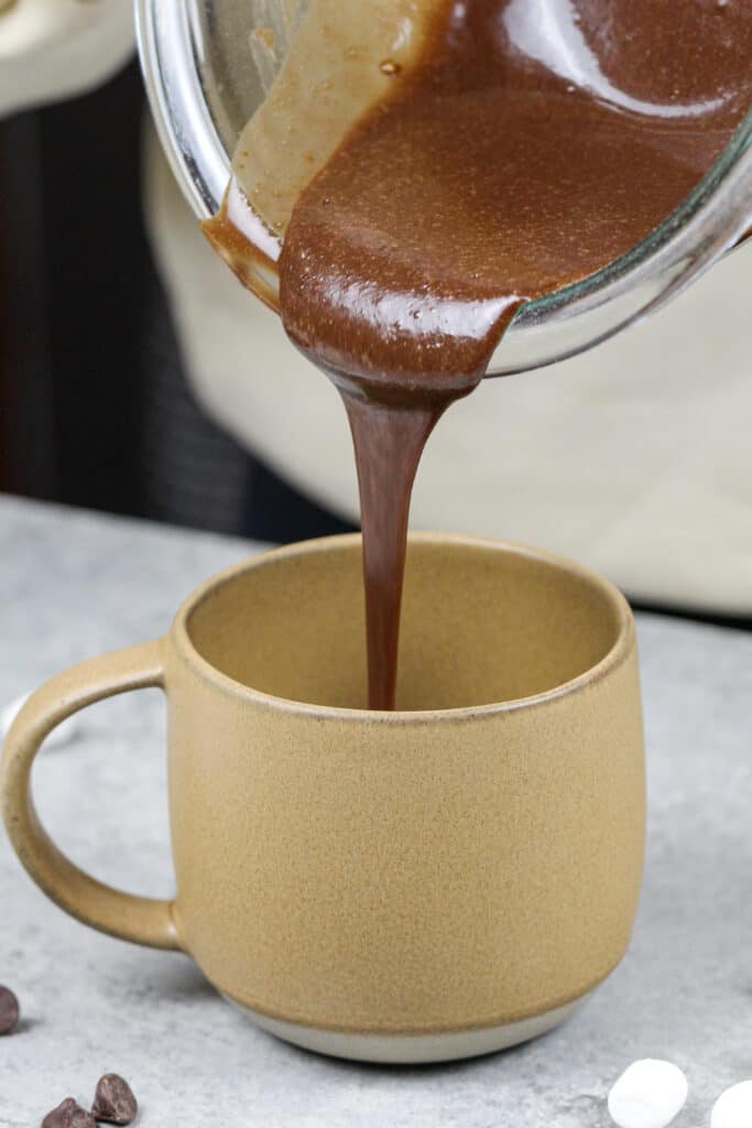 图像的巧克力蛋糕面糊倒进一个杯子,用微波炉热可可杯子蛋糕