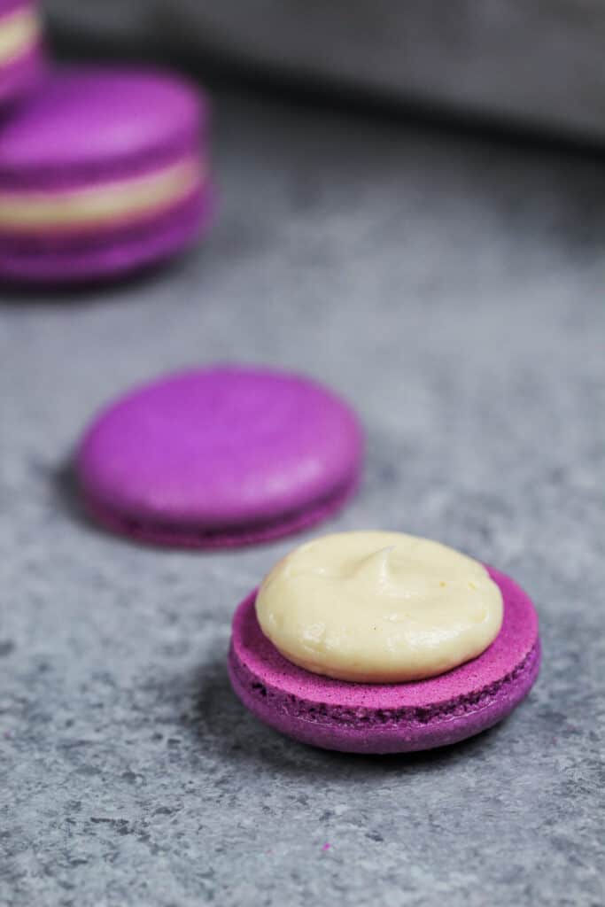 一个紫色马卡龙的外壳装满了蜂蜜薰衣草奶油，用来做蜂蜜薰衣草薰衣草马卡龙