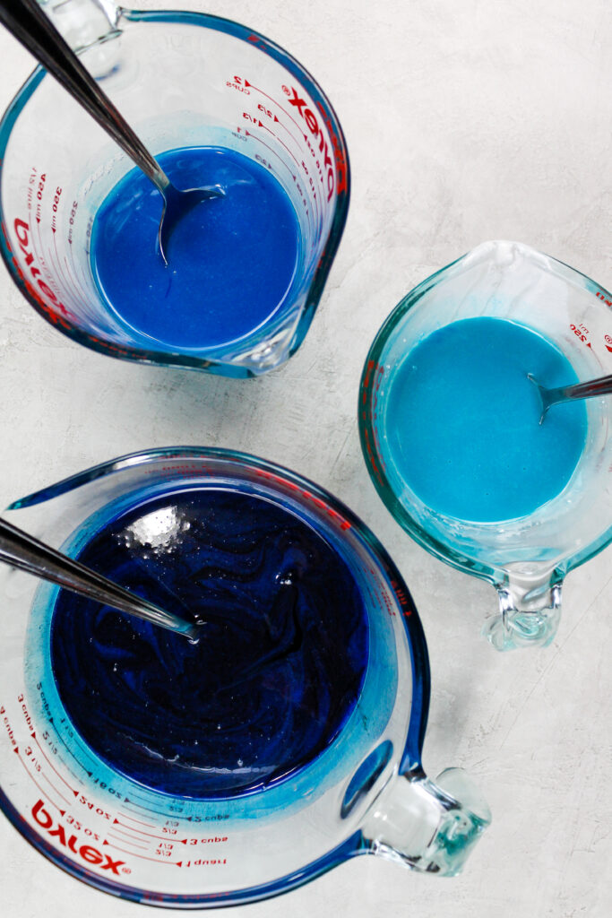 三种色调的蓝色镜面釉准备用来制作海洋主题蛋糕的图像