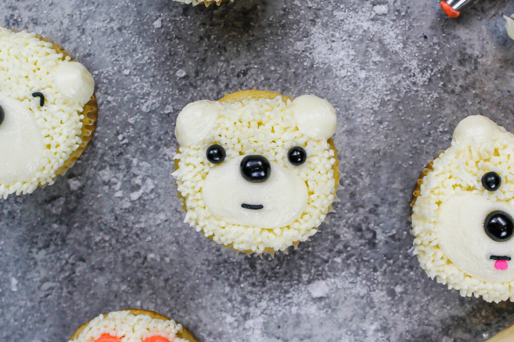 用buttercream和黑色的北极熊杯形蛋糕的图象面孔的洒