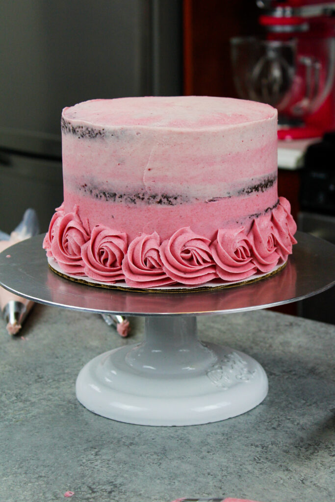 一块巧克力蛋糕的图像涂有粉红色糖霜，以匹配燕麦珠玫瑰花，这将被送到它以装饰它