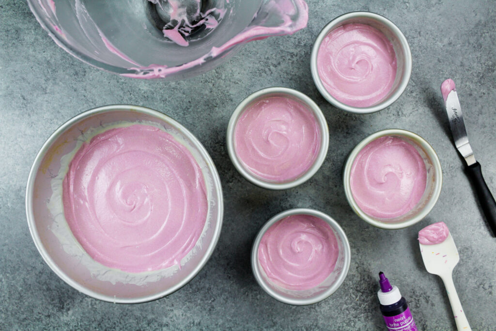 浅紫色的蛋糕糊在4英寸的平底锅和一个圆形的半圆穹顶锅准备做一个河马蛋糕烤