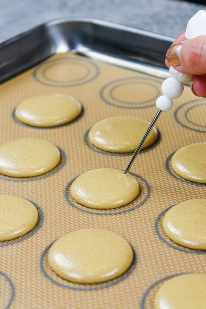 咖啡马卡龙壳的形象被用管道和撞击在柜台释放任何气泡，这些气泡被划线