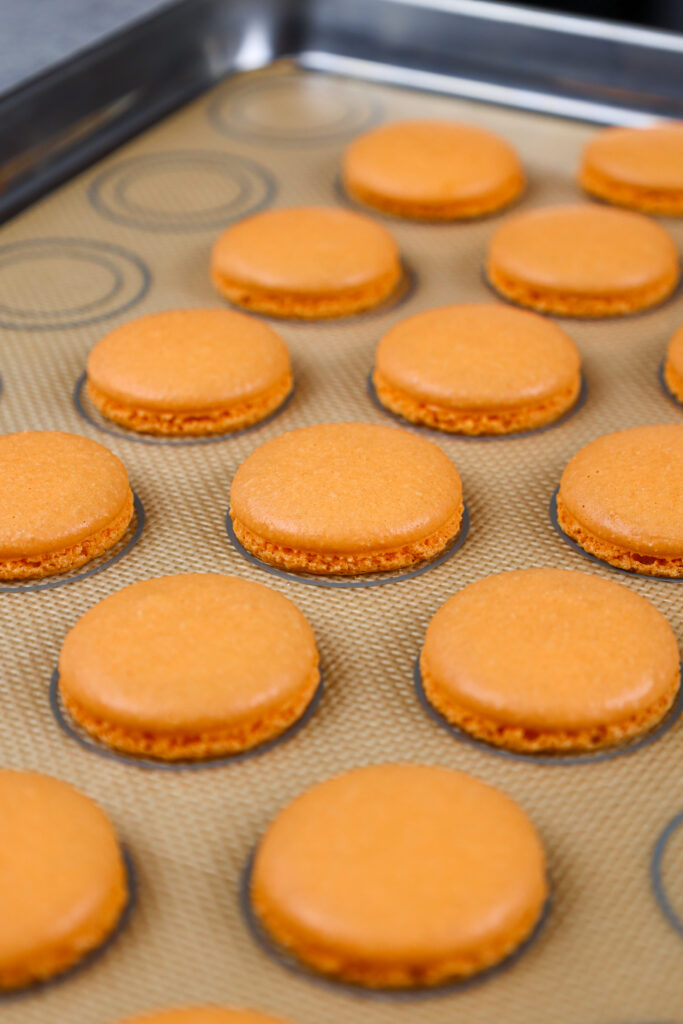 被烘烤并且有适当的脚的橙色macaron壳的图象