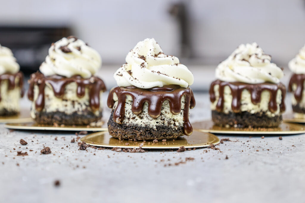 迷你奥利奥芝士蛋糕排成一行，装饰着巧克力甘纳许和生奶油