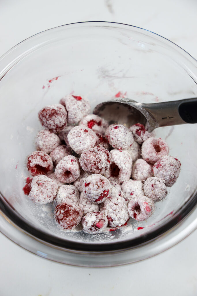 覆盆子扔在面粉中的图像，以防止它们下沉，因为这些覆盆子蛋糕烘烤