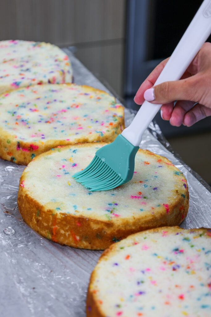 简单的糖浆的图象被刷在funfetti蛋糕层上