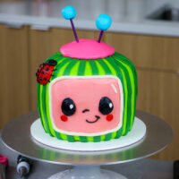 用红色天鹅绒蛋糕层制造的Buttercream Cocomelon蛋糕的图象