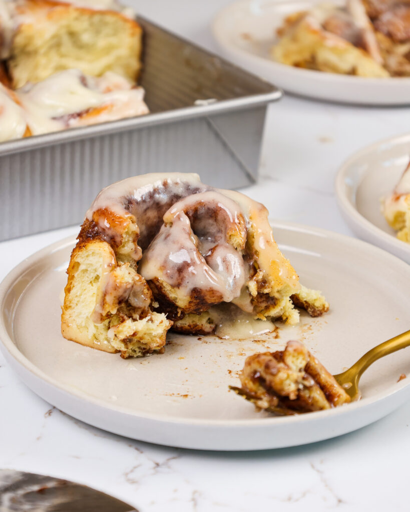 盘子上的快速酵母肉桂卷的图像被切入的盘子，以显示它的柔软和蓬松