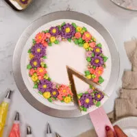 用粉红色，紫色和黄色奶油花装饰的黄油花蛋糕的图像