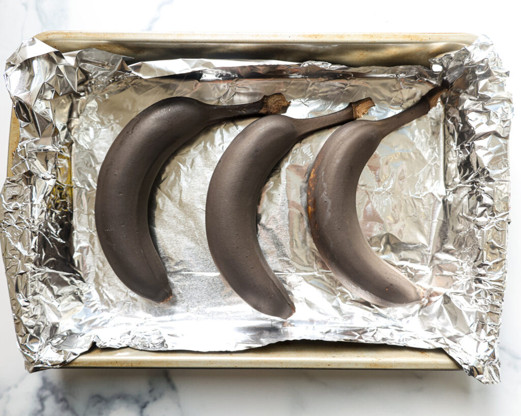 形象的未熟香蕉放在衬托着迅速成熟的烤盘烤烤箱