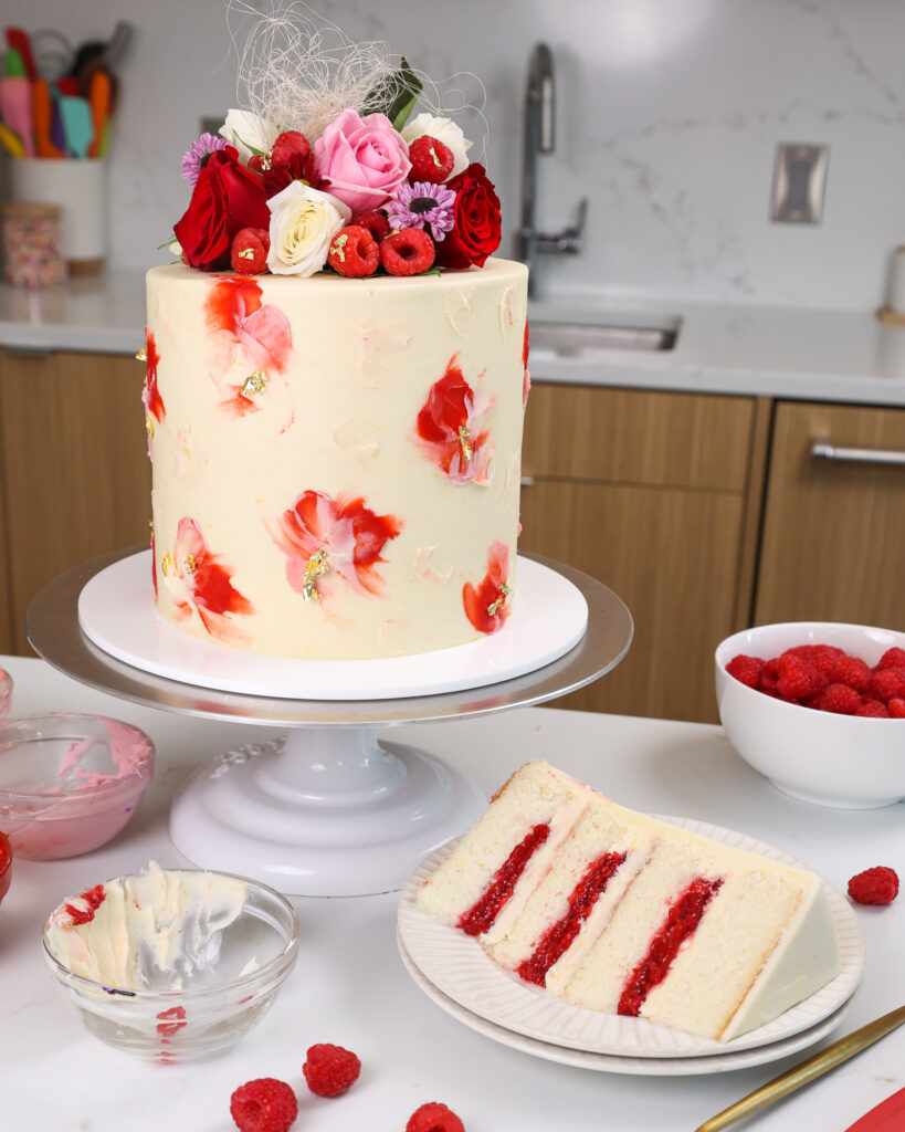 白巧克力覆盆子蛋糕的图像，该蛋糕是用蓬松的香草蛋糕层制成的