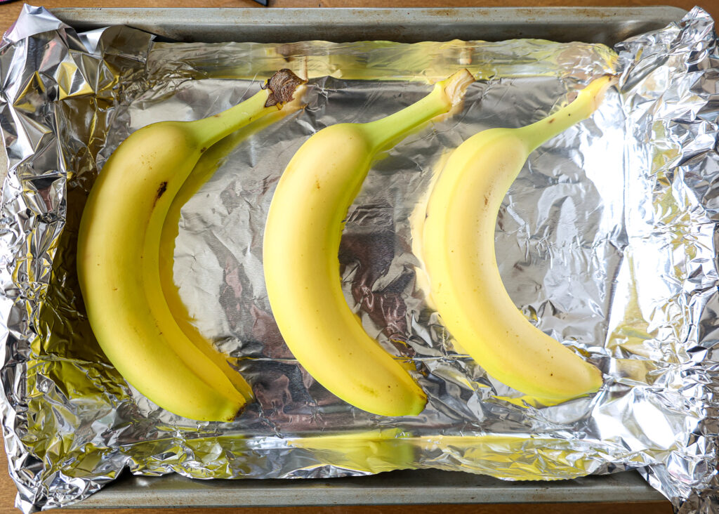 图像的未熟香蕉放在衬托着烤箱里烤盘快速成熟