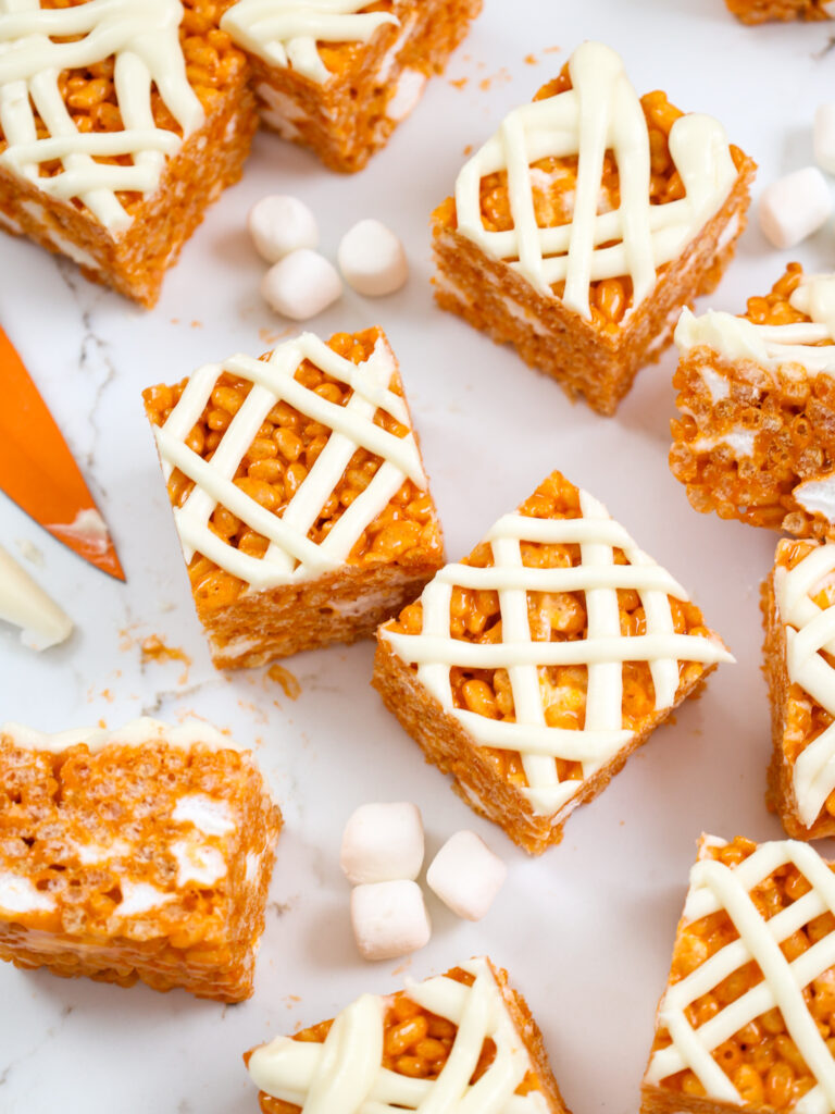 南瓜米krispie零食的图像被切成正方形，上面放上奶油奶酪糖霜