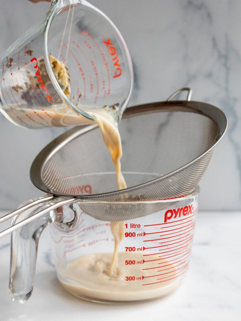 image of lavender earl grey steeped milk being poured through a strainer