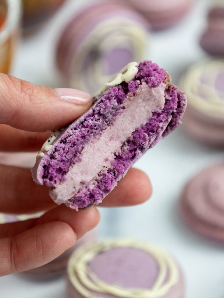 伯爵灰色马卡龙的图像，该图像被咬了，以显示其伯爵灰色奶油馅料