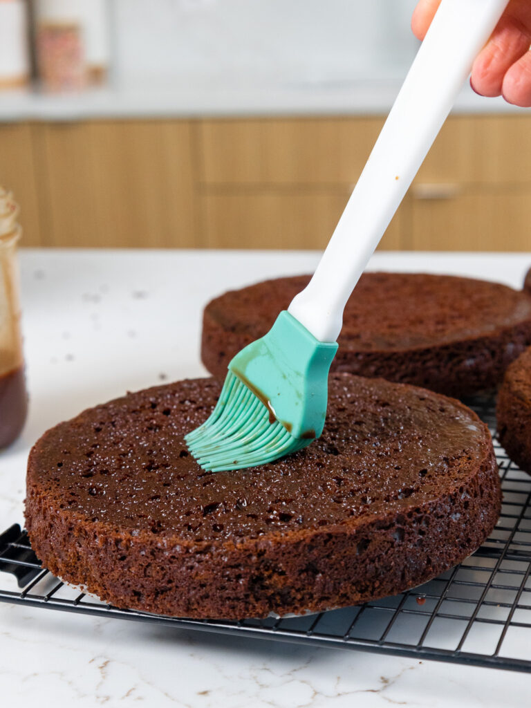 巧克力简单糖浆的图像被刷到潮湿的巧克力蛋糕层上以制成花生酱蛋糕